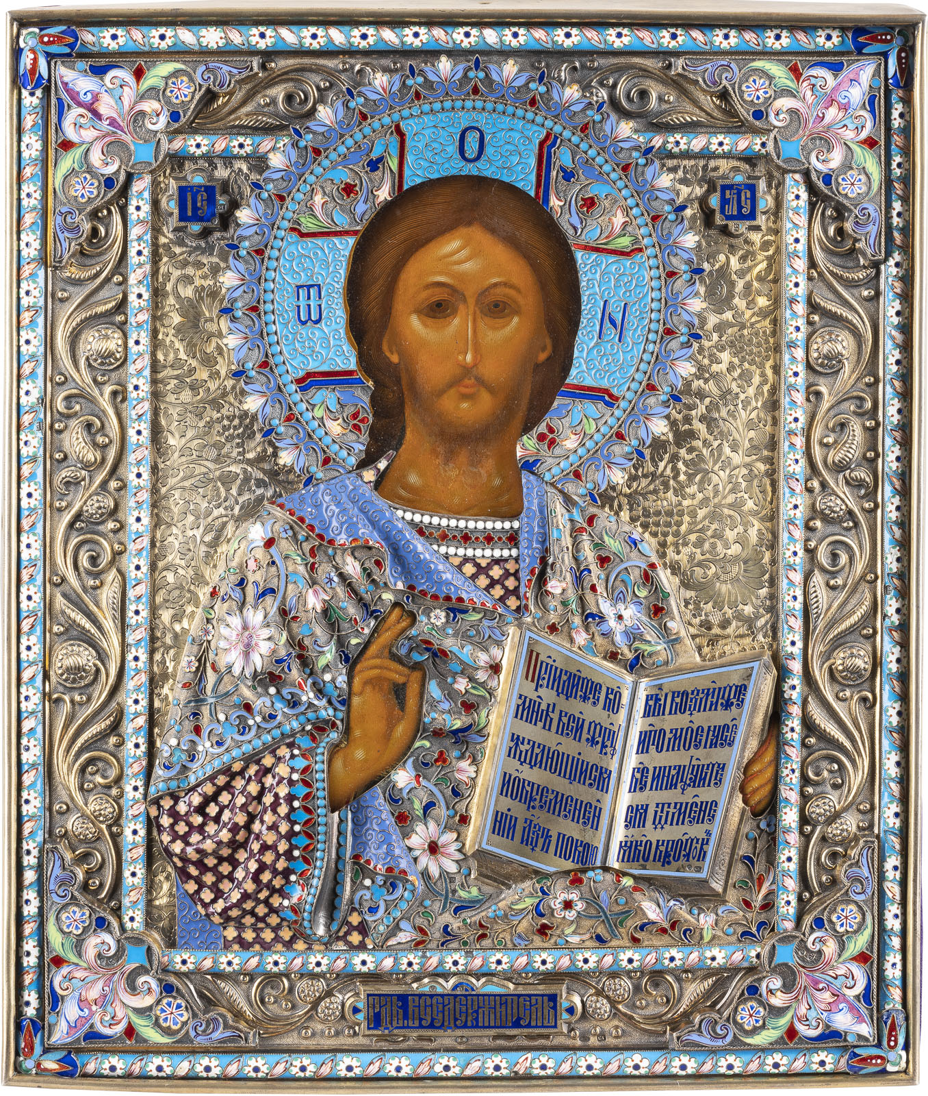 Detailreiches, orthodoxes Ikonengemälde, das Jesus Christus darstellt, umgeben von einem aufwendigen, silbernen und blau verzierten Heiligenschein. Jesus trägt eine bestickte blaue und weiße Gewandung und hält ein aufgeschlagenes Buch mit kyrillischer Schrift. Sein Gesichtsausdruck ist ernst und introspektiv.