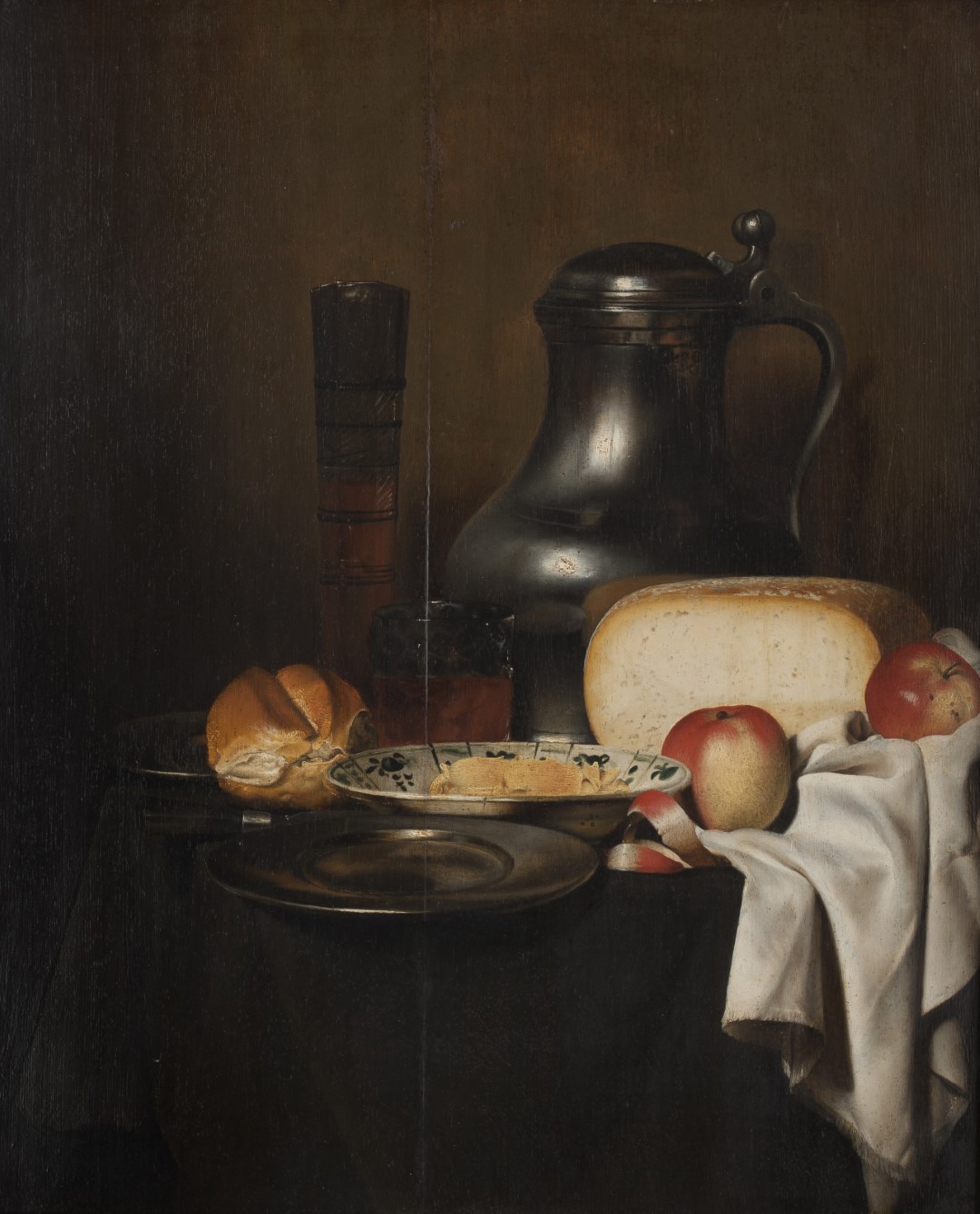 Still life from the Hargesheimer auction house in Düsseldorf. The painting depicts a dark wooden surface with an arranged ensemble of everyday objects from bygone eras. In the center of a table lie a large loaf of bread, several apples, and a plate of sliced ​​rolls. Next to it are drinking vessels, a large metal jug, and a slate stone.