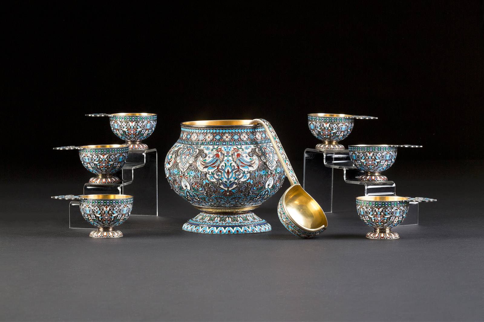 Close-up of an elaborately decorated object, presumably a vase, from an auction house. The decoration features intense blue, red, and green colors with floral and geometric patterns framed by golden lines. It impresses with its detailed ornamentation and precise craftsmanship.