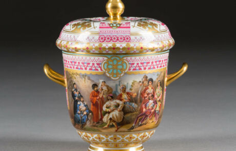 SEHR FEINES DREITEILIGES SERVICE MIT DEN VÖLKERN RUSSLANDS Detailreich verzierter antiker Porzellanpokal mit farbenfrohen historischen Szenen und Goldakzenten, ausgestellt bei einer Kunstauktion.