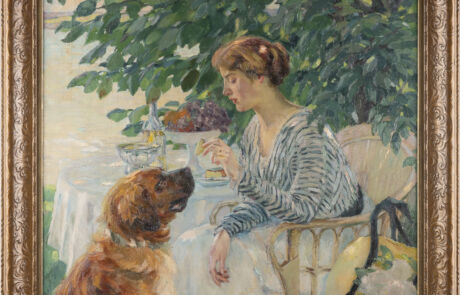 EDWARD CUCUEL 1875 San Francisco – 1954 Pasadena/USA Ein Leckerbiss Ölgemälde einer jungen Frau am Tisch im Gespräch mit einem Hund, umgeben von grüner Laubkulisse.
