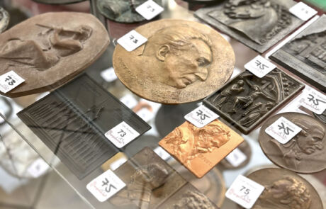 Nahaufnahme von historischen Reliefs und Medaillons in einer Vitrine bei der Kunstauktion Hargesheimer.